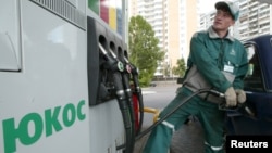 FILE - A worker fills up a car at Yukos gas station in Moscow.