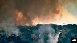 Un hélicoptère lutte contre les flammes provenant d'un incendie de forêt dans la région de Tujunga à Los Angeles, vu depuis Burbank, en Californie, le 1er septembre 2017.