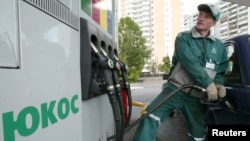 FILE - A worker fills up a car at a Yukos gas station in Moscow.