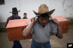 FILE - An Ixil Mayan carries the remains of a civil war victim to a memorial for a mass burial in Santa Avelina, Guatemala, Nov. 30, 2017.