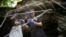 FILE - Researchers set up equipment for catching bats in front of a cave at Sai Yok National Park in Kanchanaburi province, west of Bangkok, Thailand, Friday, July 31, 2020. (AP Photo/Sakchai Lalit)