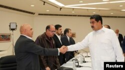 Presiden Venezuela Nicolas Maduro (kanan) berjabat tangan dengan sekjen koalisi Persatuan Demokrat (MUD), Jesus Torrealba (kiri) di Caracas, Venezuela, 30 Oktober 2016 (Miraflores Palace/Handout via REUTERS).