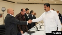 Venezuela's President Nicolas Maduro (R) shakes hands with Jesus Torrealba, secretary-general of Venezuela's coalition of opposition parties, during a political meeting between the government and the opposition, in Caracas, Venezuela, Oct. 30, 2016.