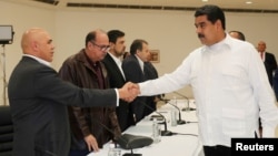 FILE - Venezuela's President Nicolas Maduro, right, shakes hands with Jesus Torrealba, left, secretary of Venezuela's coalition of opposition parties, during a political meeting between government and opposition, in Caracas, Venezuela, Oct. 30, 2016.