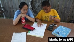 In this Tuesday, October 11, 2010 photo, Monica Zheng, an 18-year-old volunteer and student at the University of Chicago, tutors Joshua Williams, 11, as he does his homework outside the Blackstone Bicycle Works in Chicago.