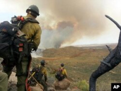 FILE - In this photo by firefighter Andrew Ashcraft, June 30, 2013, members of the Granite Mountain Hotshots watch a growing wildfire that later swept over and killed the crew of 19 firefighters near Yarnell, Arizona.