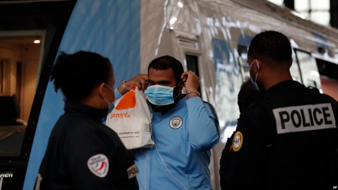Polisi meminta seorang pria untuk mengenakan masker yang wajib dipakai di stasiun kereta Saint Lazare, Paris, Senin, 11 Mei 2020.