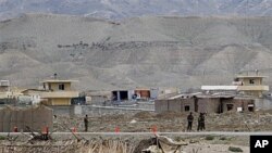 Afghan army forces stand guard as the view of the military base is seen in the background after suicide bomber has blew himself up at the entrance to the military base in eastern province of Laghman, east of Kabul, April 16, 2011