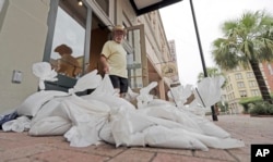 Lynn Dixon places sandbags outside their home decor store in Galveston, Texas as Hurricane Harvey intensifies in the Gulf of Mexico, Aug. 25, 2017.