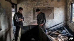 FILE - Kashmiri Muslim student Hilal Ahmed Hajam, left, and Nasir Ahmed Mir inspects the damage of a partially burned government high school in Goripora, outskirts of Srinagar, India controlled Kashmir, Nov. 1, 2016. 