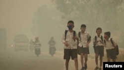 FILE - Students walk along a street as they are released from school to return home earlier due to the haze in Jambi, Indonesia's Jambi province, Sept. 29, 2015, in this picture taken by Antara Foto.