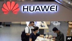 Pengunjung yang mengenakan masker melihat produk terbaru di toko Huawei di Beijing pada Rabu, 15 Juli 2020. (Foto: AP/Ng Han Guan)