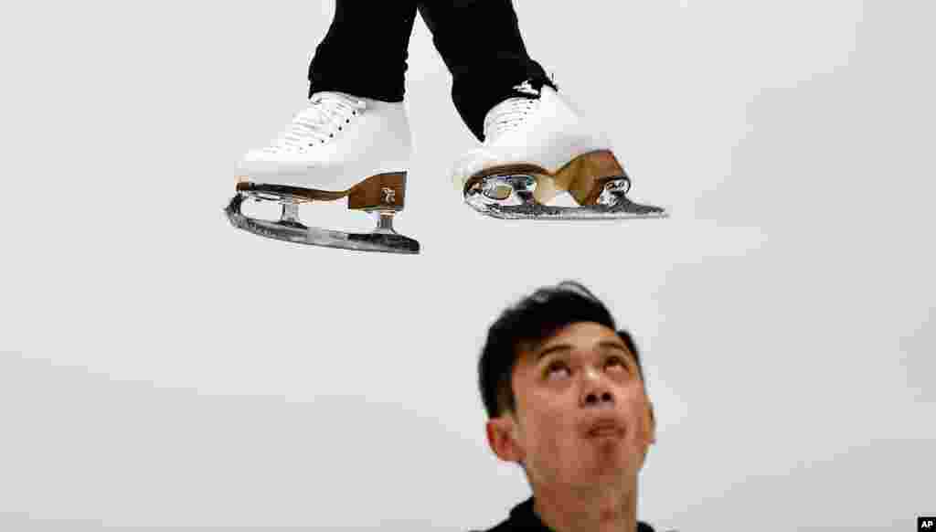 China&#39;s Yang Jin watches his partner, Cheng Peng, jumping during a practice session of the pairs at the Figure Skating World Championships in Stockholm, Sweden.