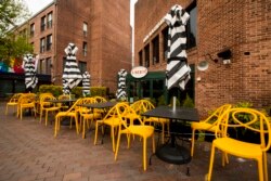 Empty chairs lines a sidewalk outside a restaurant Washington's Georgetown district, April 29, 2020. The coronavirus is sending the U.S. economy into the biggest and fastest collapse since the Great Depression, with economic output reported.