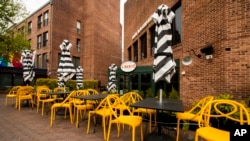 FILE - Empty chairs lines a sidewalk outside a restaurant Washington's Georgetown district, April 29, 2020. 