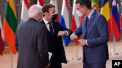 El presidente de España, Pedro Sánchez, a la derecha, saluda a su homólogo francés, Emmanuel Macron, centro, con un golpe en el codo durante la llegada a una cumbre de la UE en el edificio del Consejo Europeo en Bruselas, el 10 de diciembre de 2020.