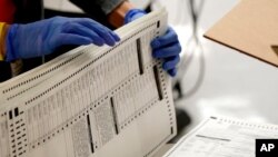 FILE - Maricopa County elections officials count ballots at the Maricopa County Recorder's Office in Phoenix, Nov. 4, 2020. 