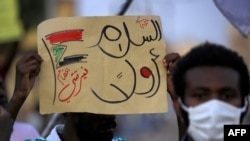 A demonstrator holds up a sign reading in Arabic "peace first, Nertiti sit-in" along with a drawn Sudanese flag, during a protest in the Garden City district of Sudan's capital Khartoum on July 4, 2020.