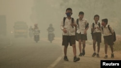 FILE - Students walk along a street as they are released from school to return home earlier due to the haze in Jambi, Indonesia's Jambi province, Sept. 29, 2015, in this picture taken by Antara Foto.