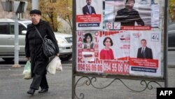 People walk past election posters in Yerevan, Dec. 6, 2018, days before Sunday's early parliamentary elections.