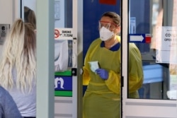 FILE - A nurse speaks with patients at the door of a new coronavirus disease clinic at Mount Barker Hospital in Adelaide, Australia, March 17, 2020.