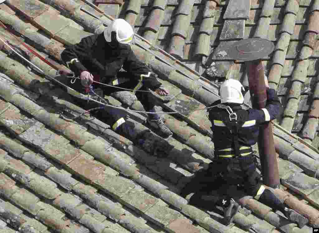 Firefighters place the chimney on the roof of the Sistine Chapel, where cardinals will gather to elect the new pope, at the Vatican. The conclave date was set during a vote by the College of Cardinals, who have been meeting all week to discuss the church's problems and priorities, and the qualities the successor to Pope Benedict XVI must possess.