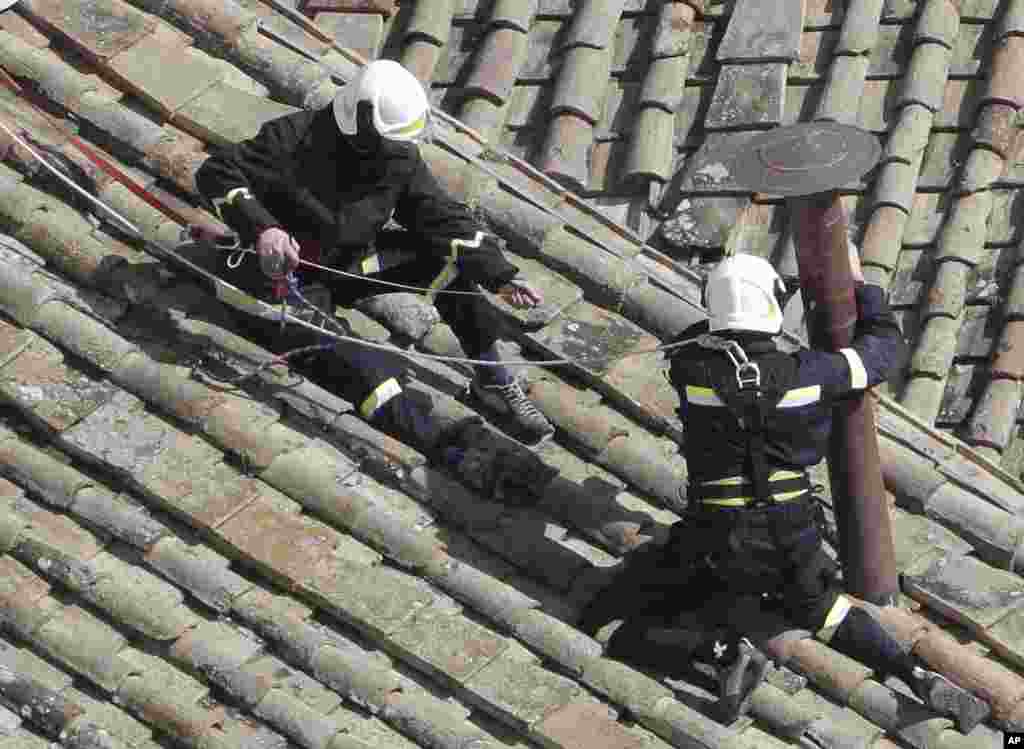 Firefighters place the chimney on the roof of the Sistine Chapel, where cardinals will gather to elect the new pope, at the Vatican. The conclave date was set during a vote by the College of Cardinals, who have been meeting all week to discuss the church&#39;s problems and priorities, and the qualities the successor to Pope Benedict XVI must possess.