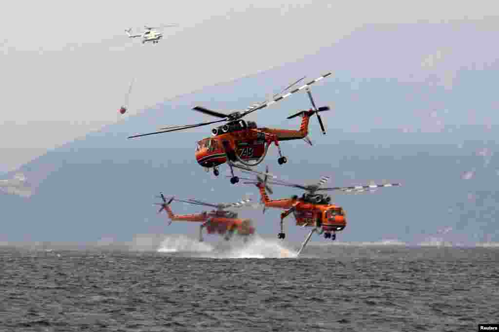 Firefighting helicopters are filled with water off the beach of the village of Pefki, on the island of Evia, Greece, Aug. 10, 2021.