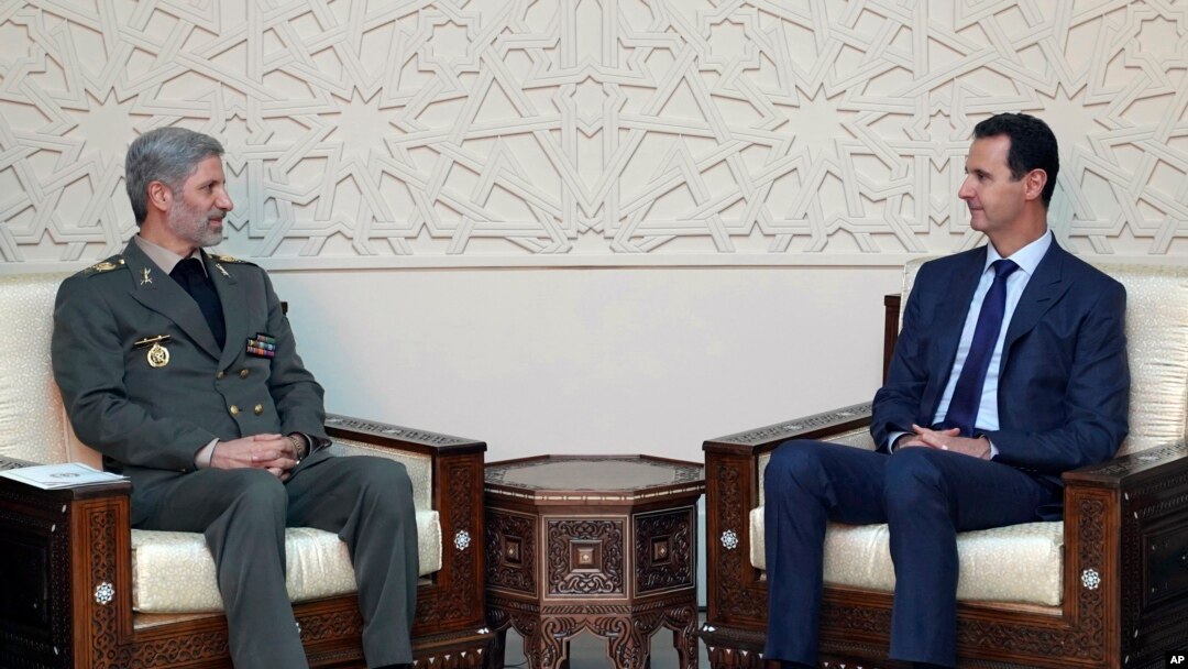 This photo released by the Syrian official news agency SANA, shows Syrian president Bashar al-Assad, right, meeting with Iran's defense minister Amir Hatami, in Damascus, Syria, Aug. 26, 2018. 