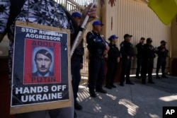 FILE—A demonstrator holds a poster showing Russian President Vladimir Putin as late German dictator Adolf Hitler to protest Russia's invasion of Ukraine outside Russia's embassy on the one-year-anniversary in Mexico City, February 24, 2023.
