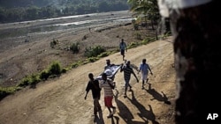 Michelet Compere, 14, suffering from cholera, is carried on a stretcher by relatives during their four-hour journey from a remote village in Pond Chevalier to the hospital in Grande Riu Du Nord village, Haiti, Nov 29, 2010