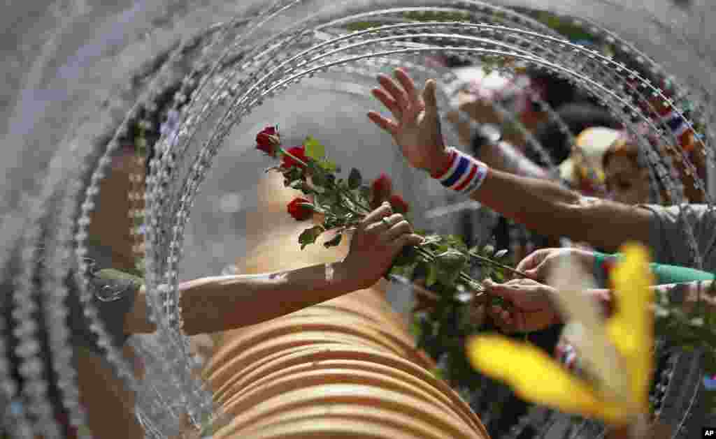 An anti-government protester gives a rose to a Thai soldier at the Defense Ministry during a rally in Bangkok.