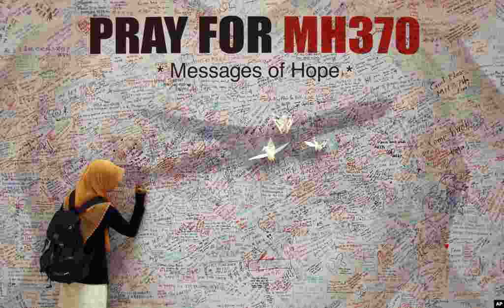 A woman writes a message for passengers aboard a missing Malaysia Airlines plane, at a shopping mall in Kuala Lumpur, Malaysia. Investigators concluded that one or more people with significant flying experience hijacked the missing plane, switched off communication devices and steered it off-course, a Malaysian government official involved in the investigation said.