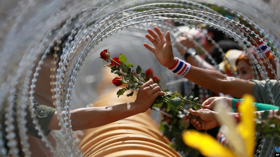 Seorang demonstran anti-pemerintah memberikan mawar pada tentara Thailand di gedung Kementerian Pertahanan di Bangkok pada demonstrasi Kamis (28/11). 