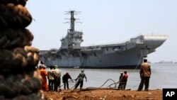 Indian navy's first aircraft carrier the INS Vikrant is drawn closer to shore at Darukhana ship breaking yard in Mumbai, India, Saturday, May 31, 2014.