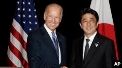 Wapres AS Joe Biden dan PM Jepang Abe berjabat tangan dalam pertemuan bilateral mereka di Singapura, Jumat (26/7). 