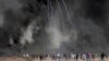 Palestinianos junto a pneus queimados, enquanto soldados israelitas atiram gás durante protestos na Faixa de Gaza. 6 de Abril