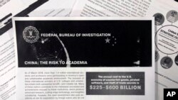 This October 4, 2019 photo shows a copy of an FBI pamphlet and related emails. The FBI’s outreach to American colleges and universities about the threat of economic espionage includes this pamphlet that warns specifically about efforts by China to steal a