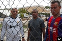 Cuban migrants Jorge Luis Hernandez, left, Johan Diaz, center, and Mike Garcia pose for photos inside a shelter set up in Mapastepec, Chiapas state, April 25, 2019.