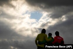 Brazil's Italo Ferreira, center, gold medal, Japan's Kanoa Igarashi, right, silver medal, and Australia's Owen Wright, bronze medal, pose for photographers in the men's surfing competition at the 2020 Summer Olympics, Tuesday, July 27, 2021