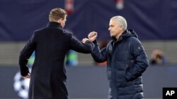 Tottenham's manager Jose Mourinho, right, and Leipzig's head coach Julian Nagelsmann touch their forearms instead of shaking hands due to the coronavirus after the Champions League round of 16, 2nd leg soccer match between RB Leipzig and Tottenham.
