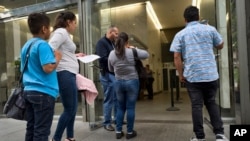 FILE - Immigrant families show paperwork to enter an immigration court in an office building in downtown Los Angeles, California, May 30, 2019.