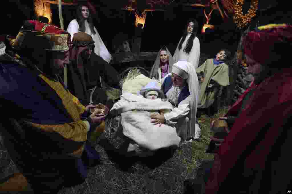 Catholic locals dressed as Joseph and Virgin Mary gather around a baby, five-moth-old Amarildo Vjerdha who plays the role of Jesus Christ, in the reenactment of the birth of Jesus Christ, in Hajmel, Albania.