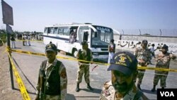 Tentara Pakistan berdiri di sekitar lokasi ledakan bom dekat dua bus di Karachi, Selasa (26/4).