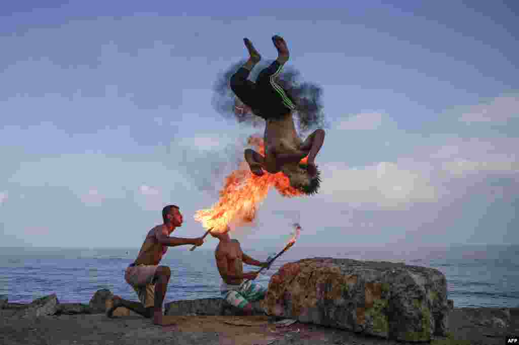 Palestinian men perform fire breathing on the beach during summer vacation in Gaza City.