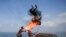 Palestinian men perform fire breathing on the beach during the summer vacation in Gaza City.