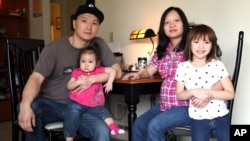 FILE - Korean adoptee Adam Crapser poses with his daughters, Christal and Christina, and his wife, Anh Nguyen, in the family's living room in Vancouver, Washington, March 19, 2015. Crapser, who was adopted as a 3-year-old from South Korea almost four decades ago and flown to America, was deported because of his criminal record, U.S. Immigration and Customs Enforcement has said. 