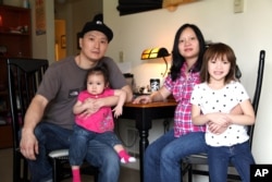 FILE - Korean adoptee Adam Crapser poses with daughters, Christal and Christina, and his wife, Anh Nguyen, in the family's living room in Vancouver, Washington, March 19, 2015.