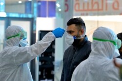 Medical staff check temperature of passengers arriving from Iran in the airport in Najaf, Iraq, Feb. 21, 2020.
