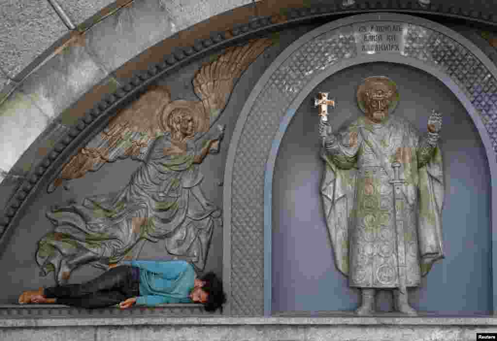 A man rests near a sculpture of Saint Volodymyr in Kyiv, Ukraine.